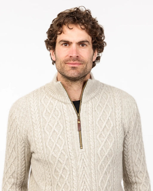Man wearing a beige cable knit sweater with a zipper